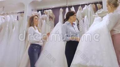 笑容可掬的新娘在婚纱店挑选白色婚纱。幸福婚姻观